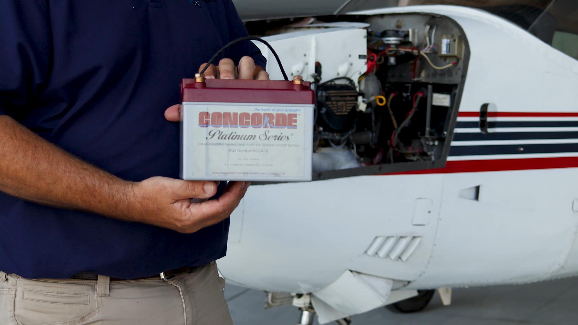 A pilot holds and aircraft battery to be installed in a Cessna 210